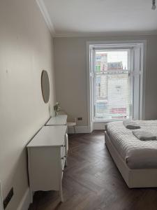 a bedroom with a bed and a desk and a window at Murraygate Townhouse in Dundee +22 photos