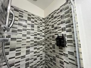 a bathroom with a shower with black and white tiles at L'icône du cinéma - Studio cosy - Gare - Centre-ville Evreux - Wifi in Évreux +21 photos