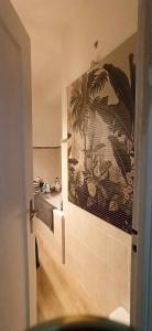 a bathroom with a painting of a palm tree on the wall at Hypercentral flat for 6 in Lorient in Lorient