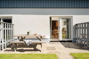 a picnic table and two benches in front of a house at Gästehaus Sulsdorf Wohnung 9 in Sulsdorf auf Fehmarn