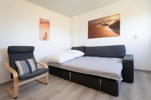 a bed and a chair in a room at Gästehaus Sulsdorf Wohnung 7 in Sulsdorf auf Fehmarn