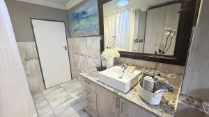 a bathroom with a white sink and a mirror at Artzy's Garden View 1km to Olivedale Clinic in Northriding +16 photos