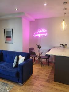 a living room with a blue couch and a neon sign at Ramsgate Rest Stylish Coastal Suite in Ramsgate +1 photo