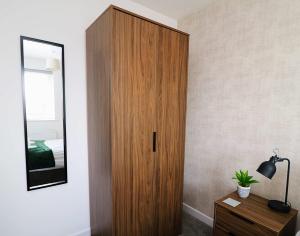 a wooden cabinet in a bedroom with a mirror at 2 Bed Semi House - Driveway Parking in Lancaster