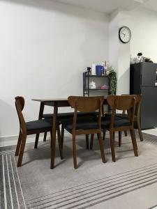 a dining room table and chairs with a clock on the wall at Puteri Homestay Melaka in Kampong Ayer Resam +4 photos