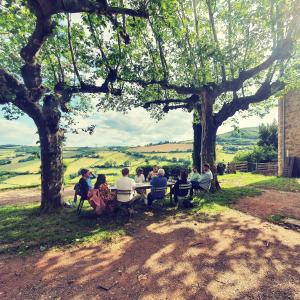 a group of people sitting at a table under trees at Clos Sauvage in Leynes