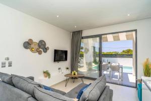 a living room with a couch and a tv at Villa Palm Vista by Villa Plus in Kremasti