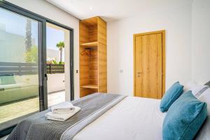 a bedroom with a large bed with blue pillows at Villa Palm Vista by Villa Plus in Kremasti +10 photos