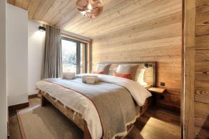 a bedroom with a large bed in a room with wooden walls at Chalet Kuma in Les Houches +31 photos