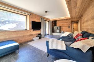 a living room with a blue couch and a tv at Chalet Kuma in Les Houches