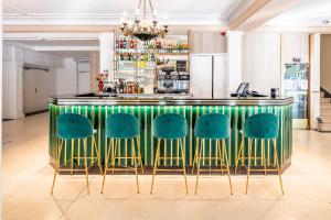 a bar with green chairs in a room at Hôtel Galilée Windsor in Lourdes