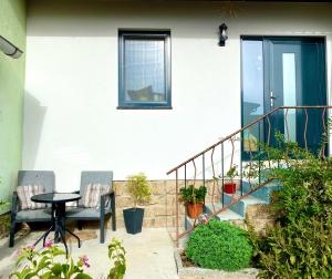 a patio with two chairs and a table and stairs at Landhaus Sonnengarten - komplettes Haus mit Garten in Langegg