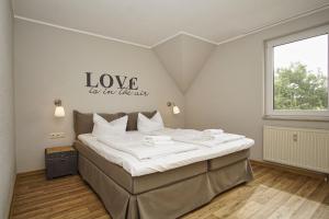 a bedroom with a bed with a love sign on the wall at strandnah mit Balkon, gratis Nutzung vom AHOI Erlebnisbad und Sauna in Sellin - Strandhaus Mönchgut FeWo16 in Lobbe +19 photos