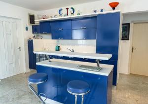 a blue kitchen with blue cabinets and stools at Luxury Beachfront Apartments Matista in Trogir +20 photos