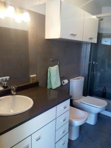 a bathroom with a toilet and a sink at ATICO PLAYA de VILARIÑO in Aldán