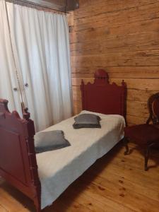 a bedroom with a bed and a window and a chair at Holiday house Mežmuiža in Rucava