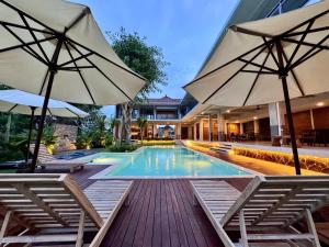 a swimming pool with two chairs and umbrellas at Nala's Home in Uluwatu