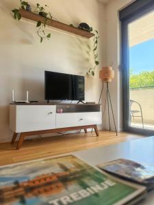 un soggiorno con TV su un centro di intrattenimento bianco di Apartman Smokvica a Trebinje