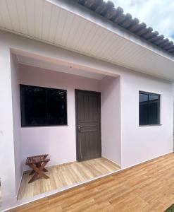 a white house with a door and a bench at Micro casa Maju in Cascavel