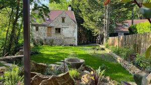a yard with a stone house with a fence at Le Moulin de Rochopt in Boussy-Saint-Antoine