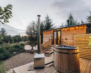 a wooden cabin with a hot tub on a deck at The Wildflower Shepherd's Hut in Matfen