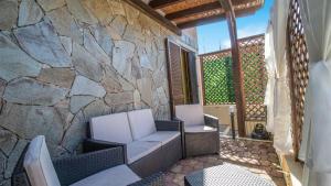a patio with two chairs and a stone wall at Domus Peppi in Villasimius