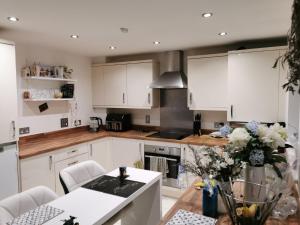 eine Küche mit weißen Schränken und einem Tisch mit Blumen in der Unterkunft The Grange Cute Modern Stay in Gerrards Cross