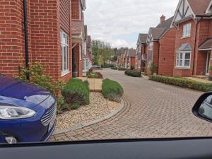 ein blaues Auto, das auf einer gepflasterten Straße mit Häusern geparkt ist in der Unterkunft The Grange Cute Modern Stay in Gerrards Cross