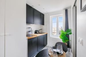 a kitchen with black cabinets and a table with wine glasses at Studio cosy proche Paris et du Bois de Vincennes in Charenton-le-Pont