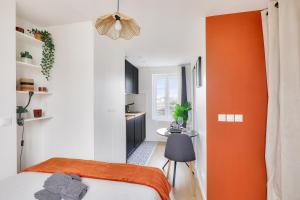 an orange and white bedroom with a bed and a desk at Studio cosy proche Paris et du Bois de Vincennes in Charenton-le-Pont
