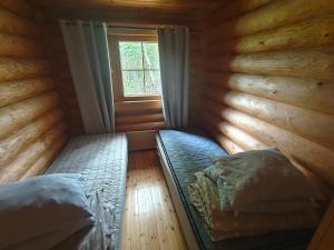 a small room with two beds in a room with a window at Kalliorinteen Mökit Havupirtti in Töysä