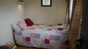 a bedroom with a bed with a quilt on it at Shepherds Hut at Rhyd y Galen in Llanrug