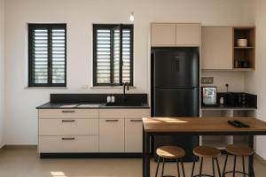 a kitchen with a refrigerator and a table with stools at סוויטת בארי , שלווה בגליל העליון in Mishmār Hāyardin