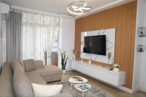 a living room with a couch and a tv on a wall at Cosmos Apartment in Shkodër