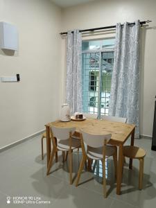 - une table et des chaises en bois dans une chambre avec fenêtre dans l'établissement Minimalist Homestay Dungun, à Kampong Sura Tengah