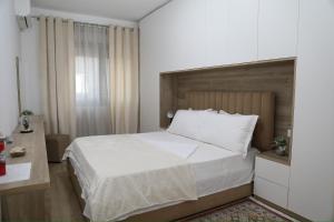 a bedroom with a large white bed and a window at Cosmos Apartment in Shkodër