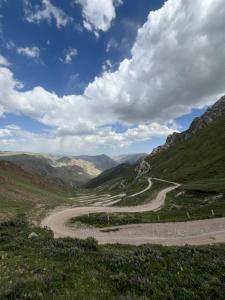 een kronkelende weg in de bergen onder een bewolkte hemel bij One Million Stars Yurt camp in Song-Kul