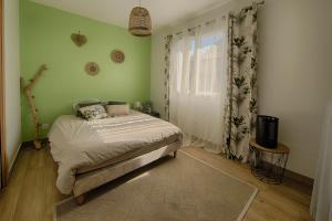 een slaapkamer met een bed met groene muren en een raam bij Maison Landes in Mées +6 foto's