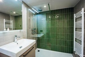 a bathroom with a sink and a shower with green tiles at Brera Serviced Apartments Böblingen Sindelfingen in Böblingen