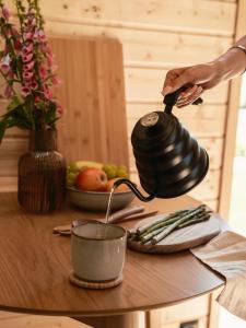 a person pouring coffee into a tea pot on a table at Sosnowy Szept in Karpacz