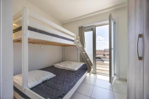 a bedroom with bunk beds and a balcony at Volledig gerenoveerd 2 slaapkamer appartement in Westende-Bad, 250 m van het strand in Westende Bad