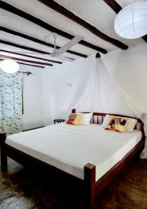 una camera da letto con un grande letto bianco in una stanza di Simba House a Watamu