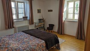 a bedroom with a bed and two windows and a chair at Appartement Melou rez de chaussée in Gérardmer