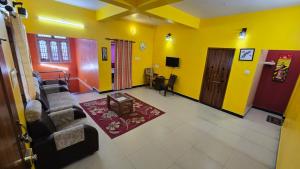 a living room with a couch and yellow walls at Hill Top Home Stay ooty in Ooty