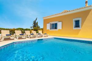 a swimming pool with chairs and a house at Villa Palms by Algarve Vacation in Albufeira