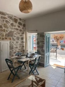 a dining room with a table and chairs and a stone wall at Seaside House in Symi