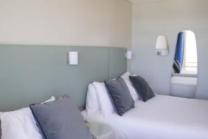 a hotel room with a white bed and white pillows at Rydges Gladstone in Gladstone
