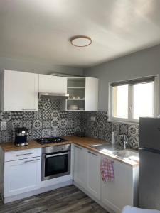 a kitchen with white cabinets and a sink at La Villa d'Elisa in Saint-Côme-de-Fresné