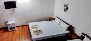 a small room with a white bed with pillows at HOTEL H1 Fianarantsoa in Fianarantsoa