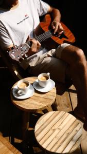 a man playing a guitar next to a table with cups of coffee at Le Phare in Les Portes